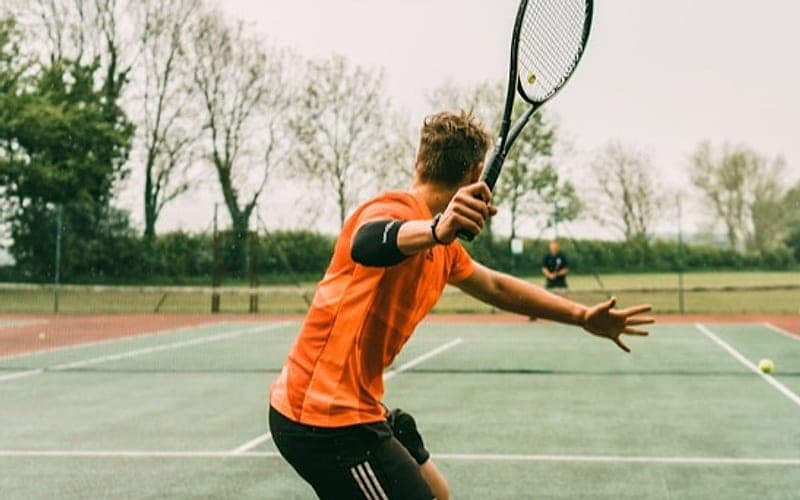 A tennis player mid-serve on an outdoor court