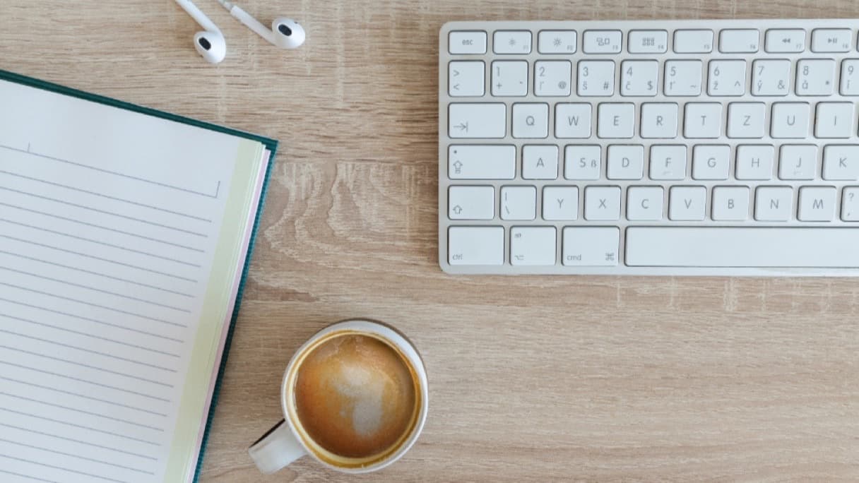 Two mugs of tea and an open notebook on a kitchen table