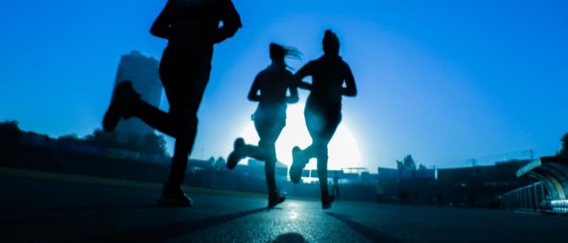 A runner mid-stride on a park path, lower legs and shoes in view