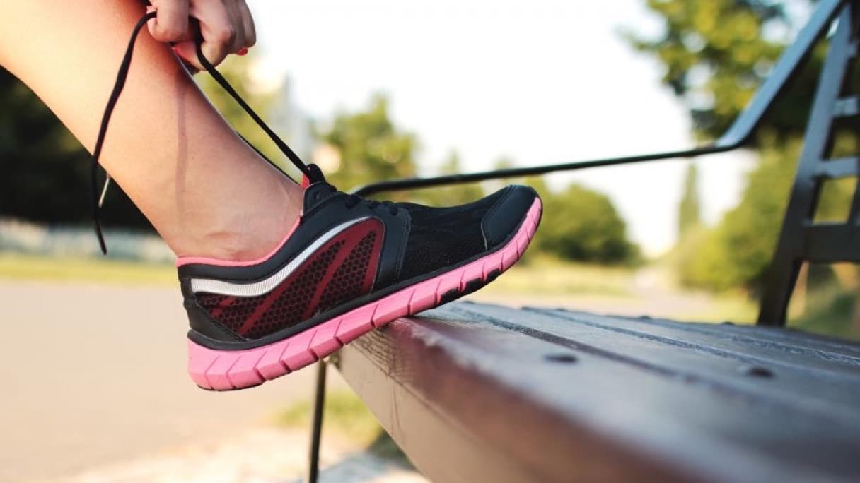 A pair of running shoes on a park bench at sunrise