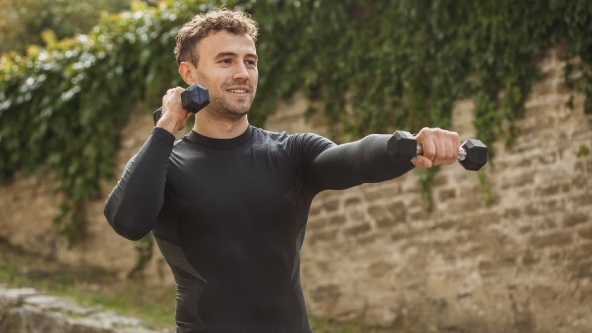Light dumbbells and a resistance band beside an exercise mat